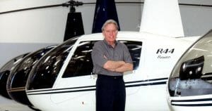 Confident man posing by helicopters bearing his name.