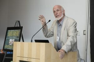 At lectern giving a lecture.