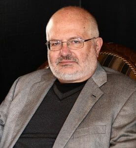 Distinguished man in a chair looking at camera.